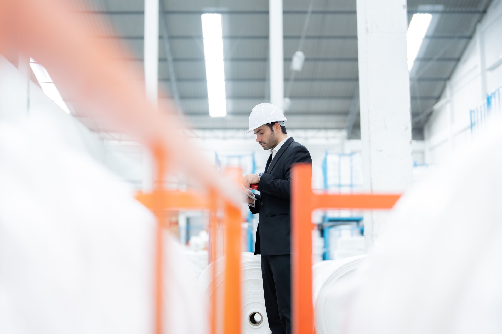 An American male engineer is reviewing an export manifest as an industrial automation solution deployed in a factory, seamlessly integrating into existing operations to increase efficiency.